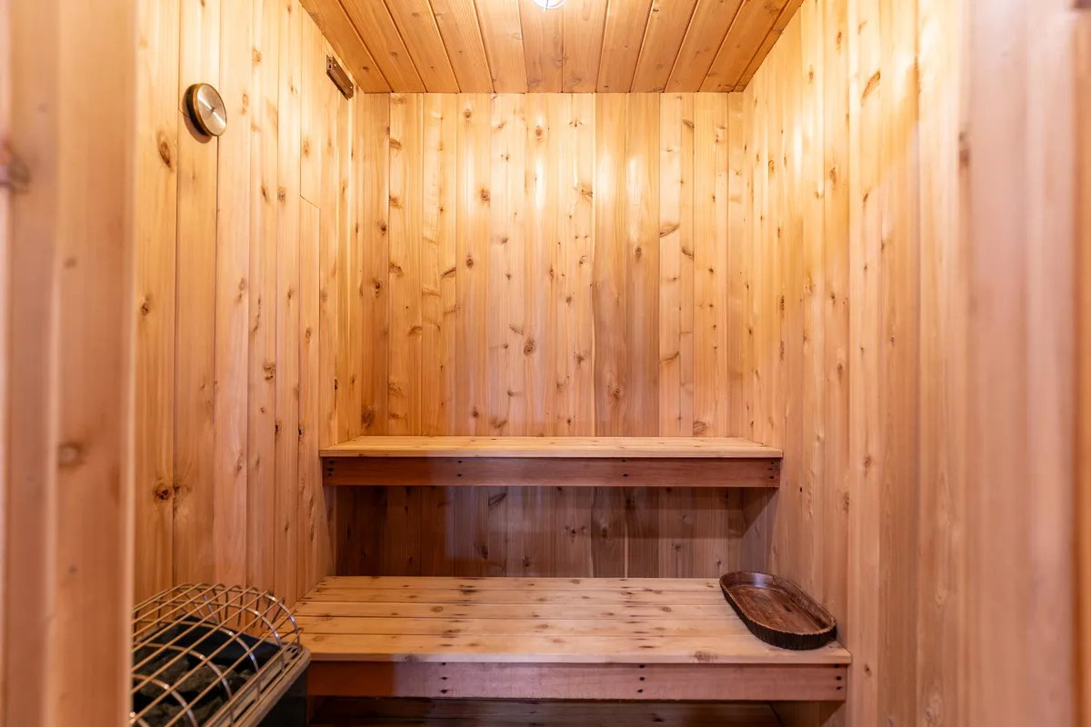 A warm, wood-paneled sauna with wooden benches and a soft overhead light, offering a tranquil space for relaxation and wellness rituals. The serene environment invites guests to unwind after a day of activities.