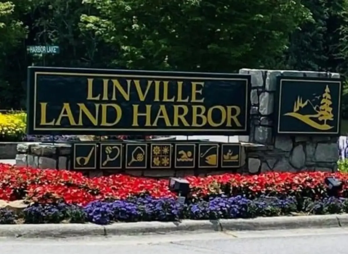 Inviting signage at the entrance to Land Harbor, surrounded by lush greenery and colorful flower beds. The setting hints at easy access to nature trails and a welcoming community atmosphere.